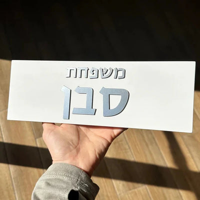 A concrete sign for a home in a personalized design, white in color with silver lettering 