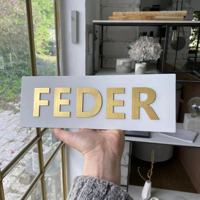 A handmade home sign made of clean white concrete with gold lettering - Israel Series 