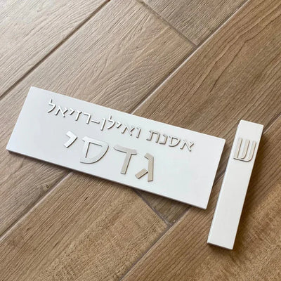 A designed sign for the entrance to a house with names made of white concrete with silver lettering - Israel series  Door Sign + Mezuzah Case