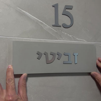 A design sign for a door made of clean concrete in gray with silver lettering - Israel series
