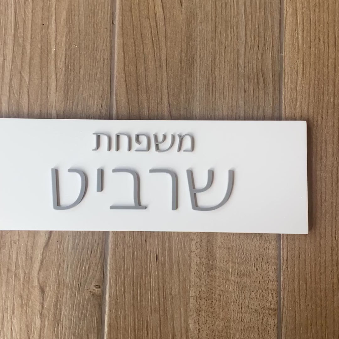 A personalized family sign with engraved names in white concrete with silver lettering