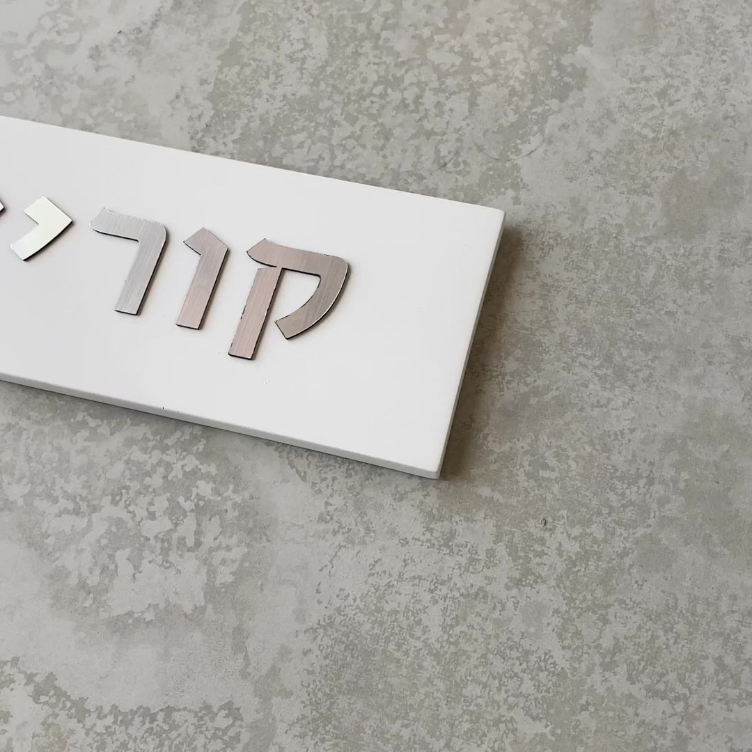 A designed sign for the entrance to a house with names made of white concrete with silver lettering - Israel series