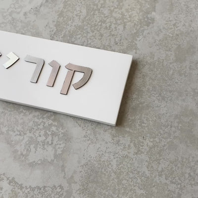 A designed sign for the entrance to a house with names made of white concrete with silver lettering - Israel series
